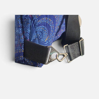 Close-up of blue Shweshwe fabric, black webbing strap, silver-tone swivel clip and adjuster.