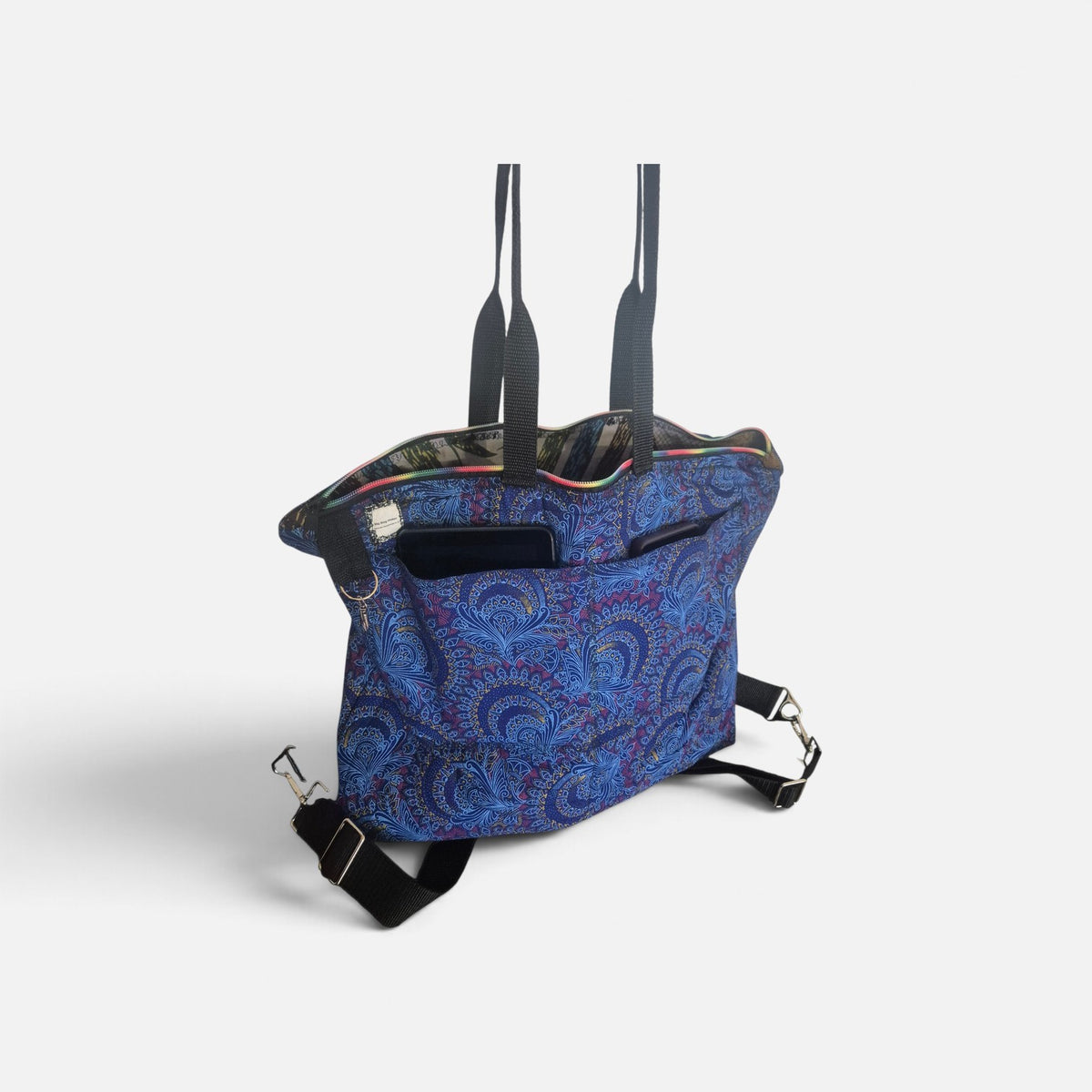 Blue Peacocks Traveller bag with blue paisley fabric, black folded handles, outer patch pockets and detachable straps.