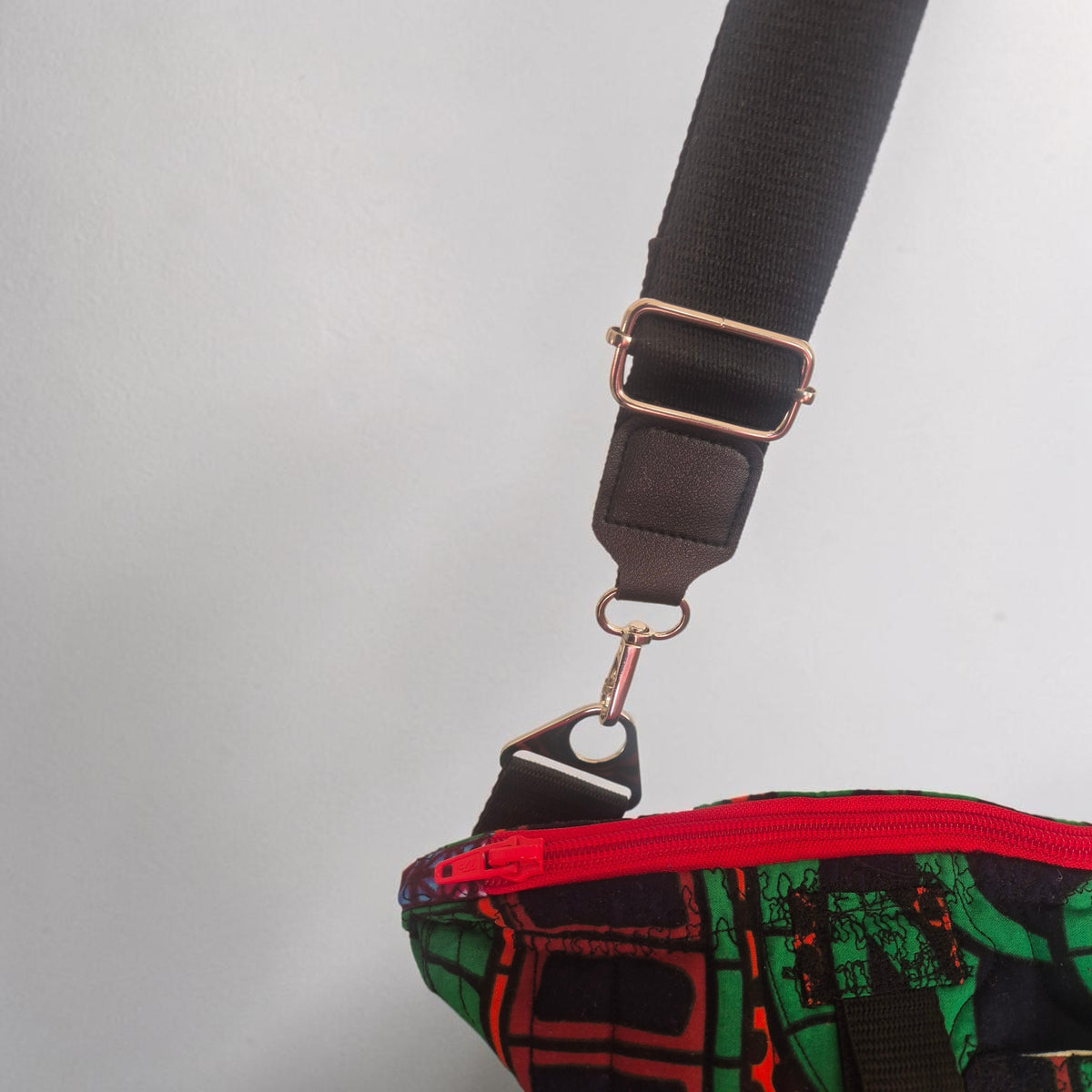 Close-up of the black adjustable strap, silver-tone swivel clasp and red zip on the Hibiscus & Sunflower bag.
