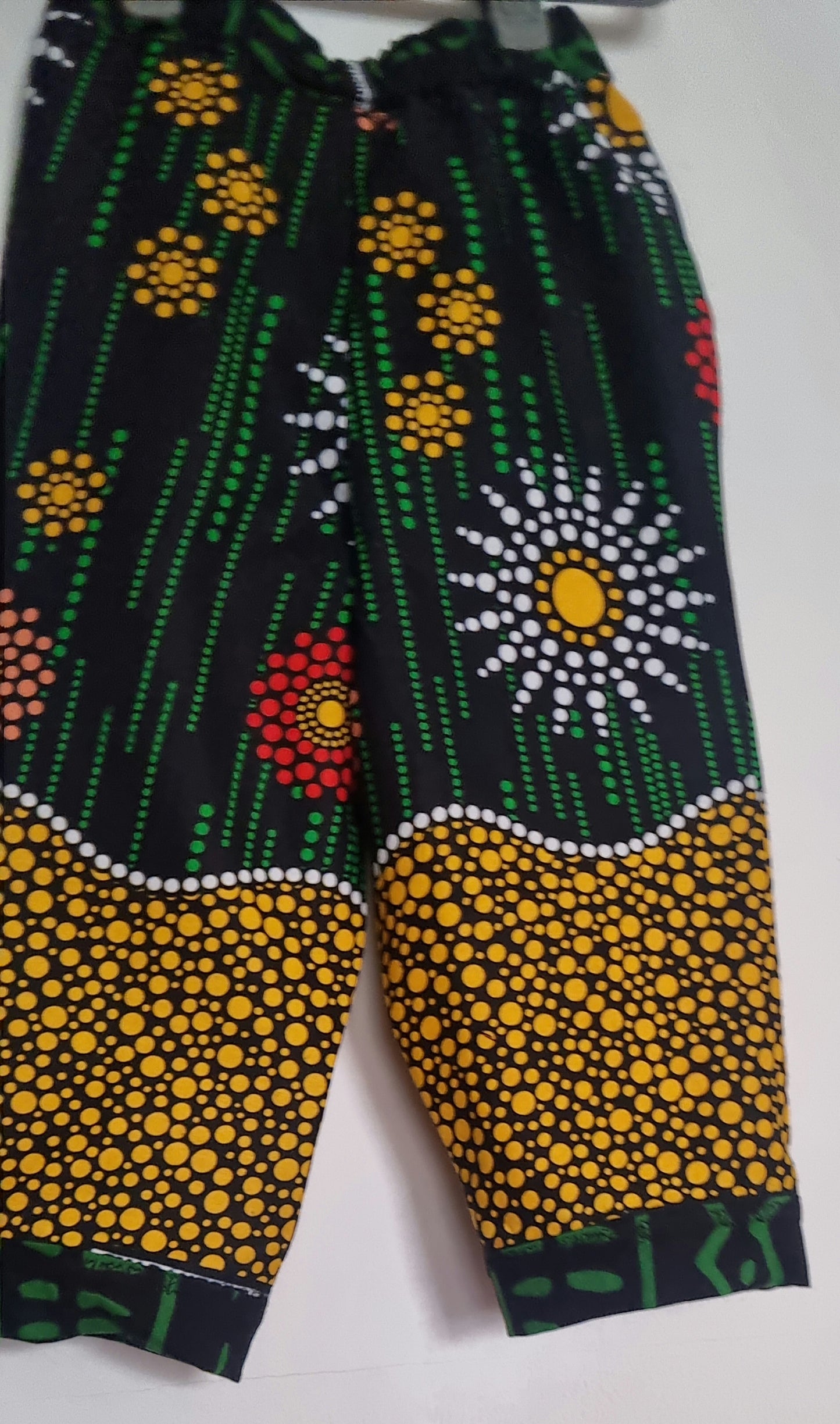 Big Bag Maker Sunburst trousers featuring a black base with vibrant yellow, red, and white floral dot patterns.