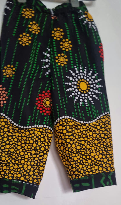 Big Bag Maker Sunburst trousers featuring a black base with vibrant yellow, red, and white floral dot patterns.