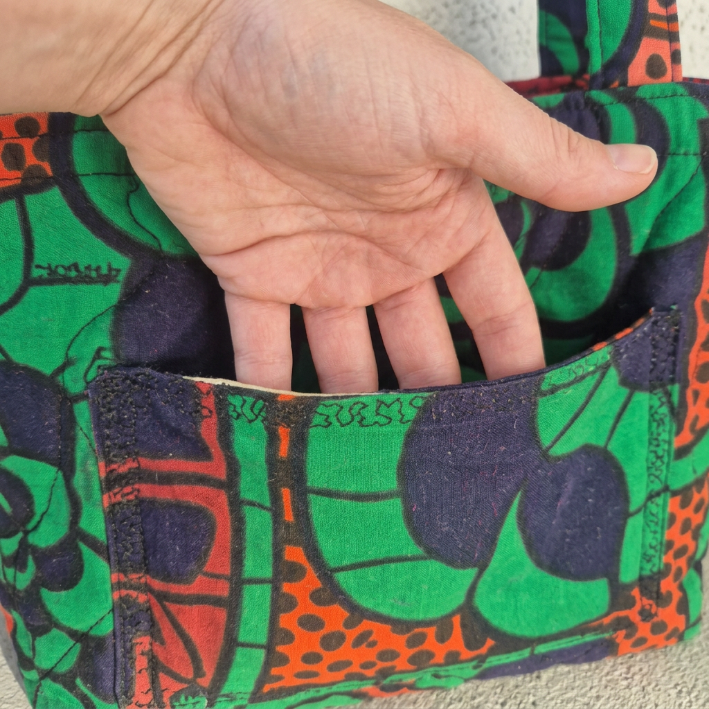 Hand slipping into the Hibiscus & Sunflower bag’s exterior pocket