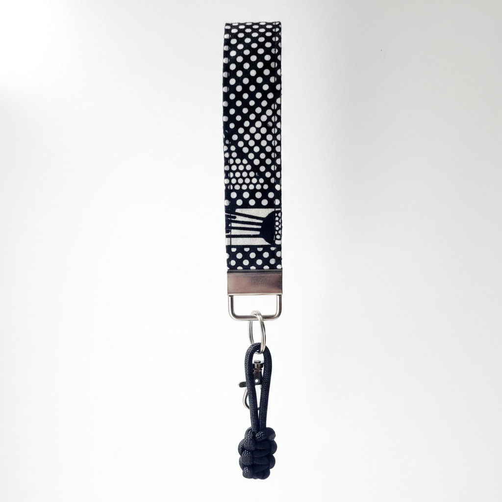 African wax print key fob wristlet in black and white geometric Dutch wax print with silver lobster clasp and black paracord charm, white background